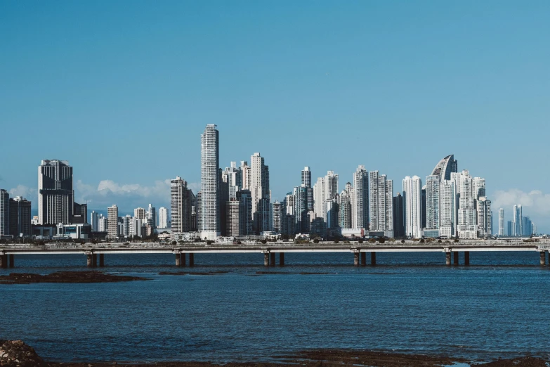 a large body of water with a city in the background, by Ceferí Olivé, pexels contest winner, hurufiyya, tall buildings on the sides, clear blue skies, gif, all buildings on bridge