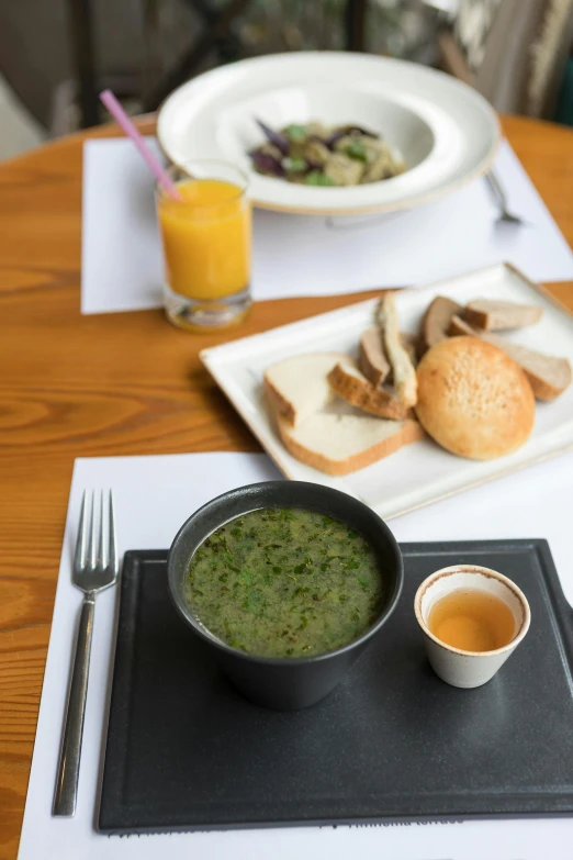 a table topped with a bowl of soup next to a plate of bread, inspired by Albert Paris Gütersloh, unsplash, in karuizawa, #green, grey, diner