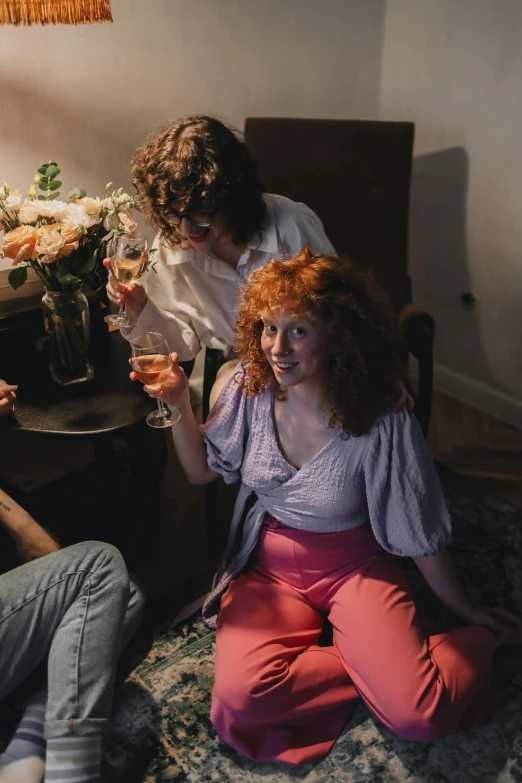 a group of people sitting on top of a living room floor, a portrait, inspired by Nan Goldin, pexels contest winner, renaissance, enjoying a glass of wine, ginger wavy hair, romantic couple, flowers around