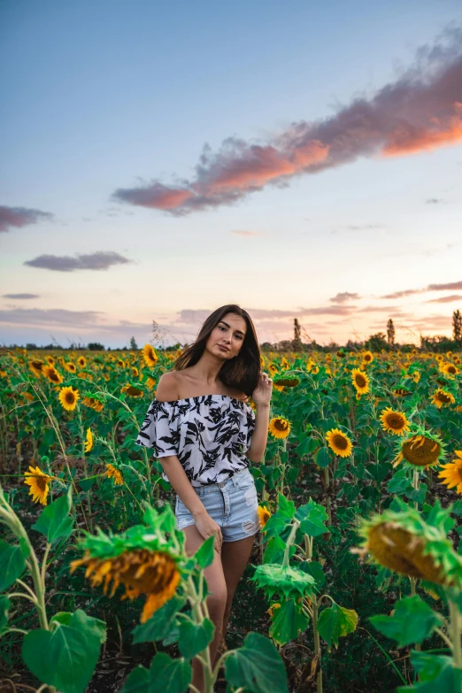 a woman standing in a field of sunflowers, a picture, by Julia Pishtar, pexels contest winner, dressed in a top and shorts, portrait emily ratajkowski, sun set, various posed