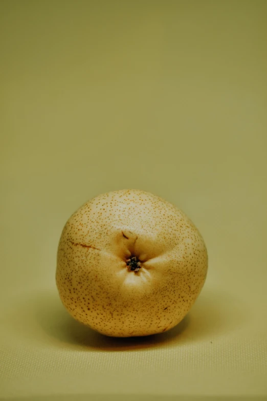 a close up of an orange on a table, by Dave Allsop, big pear-shaped head, high - resolution photograph, beige, potato