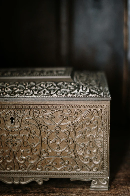 a silver box sitting on top of a wooden table, inspired by Gustav Doré, trending on unsplash, wooden cabinet, detail shot, brown, patterned