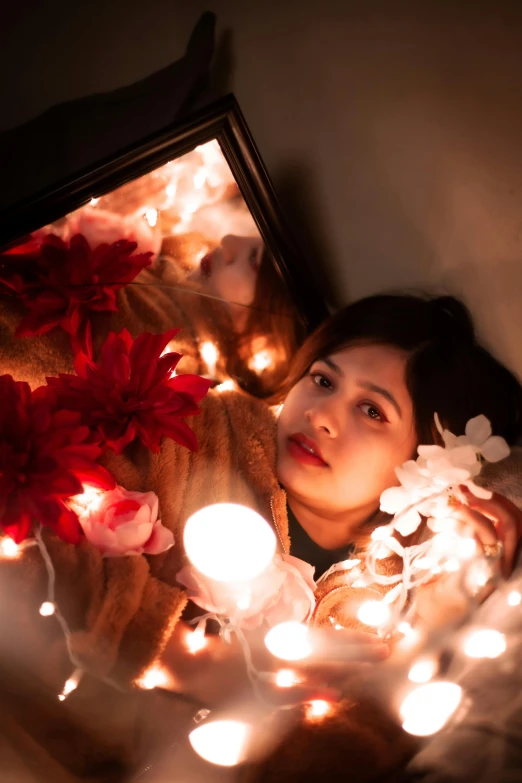 a woman laying in bed with christmas lights around her, inspired by Elsa Bleda, woman in flowers, looking into a mirror, asian woman, lit with candles