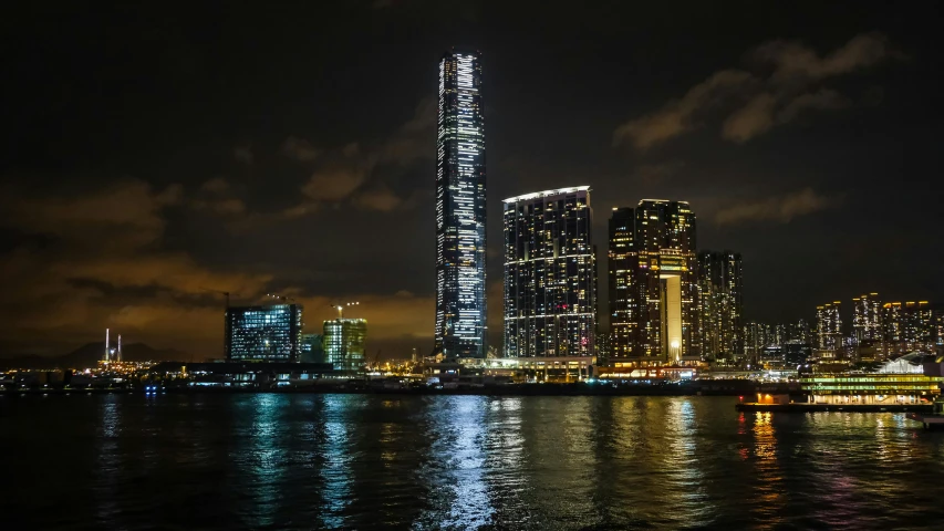 a view of a city at night from the water, an album cover, by Tom Wänerstrand, pexels contest winner, hong kong buildings, towering, youtube thumbnail, gigapixel photo