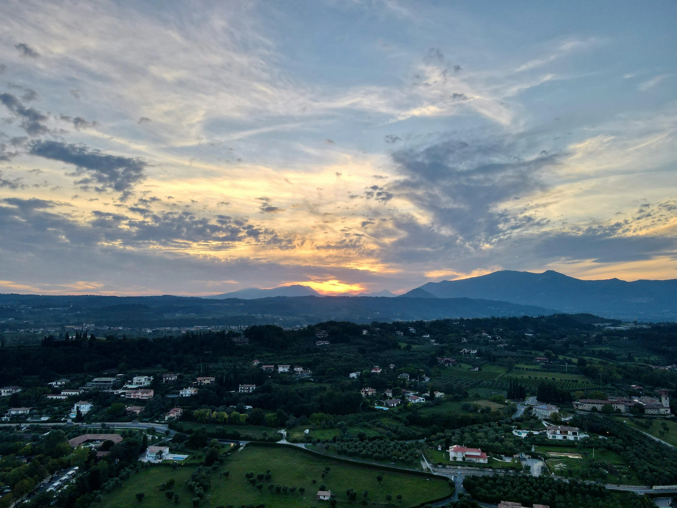 a sunset over a golf course with mountains in the background, by Alessandro Allori, pexels contest winner, renaissance, drone view of a city, overlooking a valley with trees, distant mountains lights photo