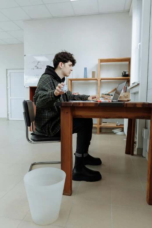 a man sitting at a table working on a laptop, pexels, arbeitsrat für kunst, finn wolfhard, full body image, - 8, low quality photo