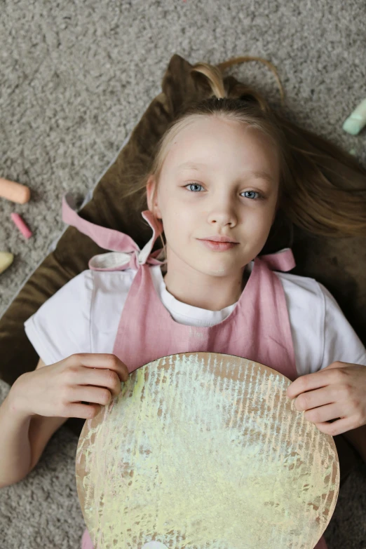 a little girl laying on the floor holding a plate, pexels contest winner, pastels, greta thunberg, 15081959 21121991 01012000 4k, flat pancake head