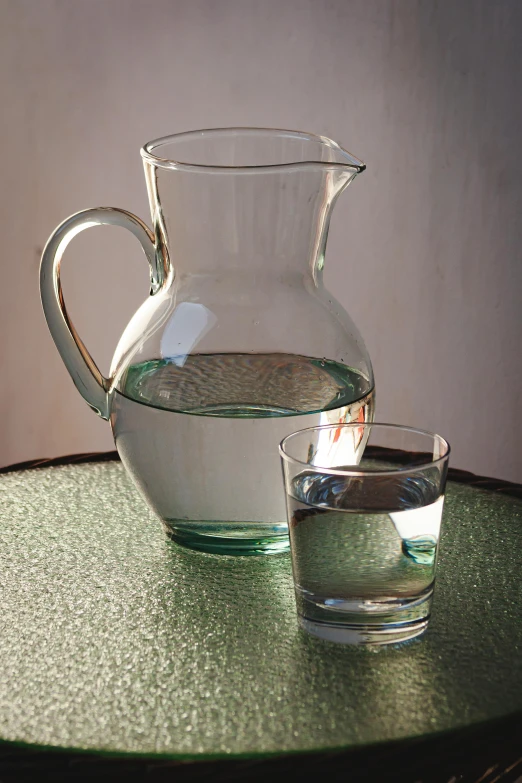 a pitcher and a glass on a table, by Jan Rustem, pixabay, photorealism, green water, halogen, tank, taken in the late 2000s