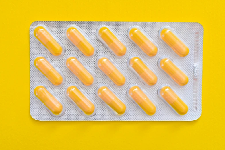 pills in a blister pack on a yellow background, by Nicolette Macnamara, antipodeans, listing image, fan favorite, yellow-orange, on grey background