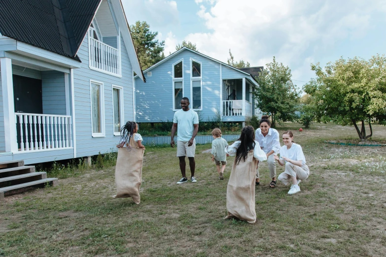 a group of people that are standing in the grass, cottage, playing games, cottagecore, sea - green and white clothes