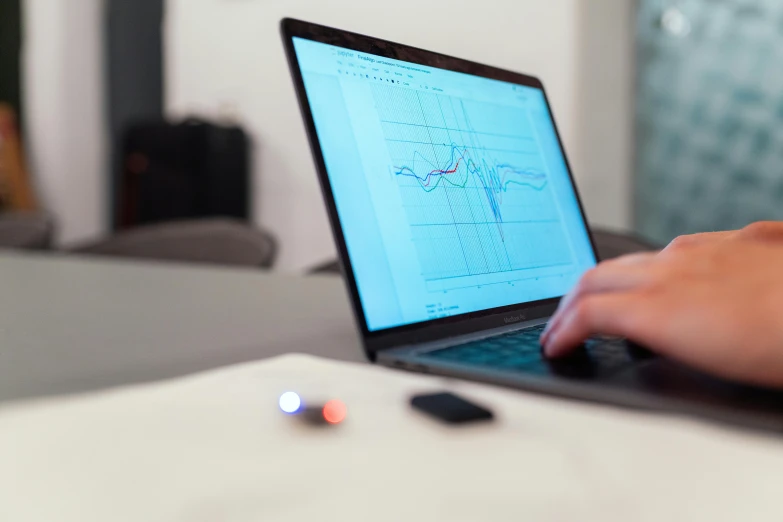 a person using a laptop computer on a desk, by Julian Allen, trending on pexels, analytical art, graph signals, tiny gaussian blur, lie detector test, mid shot photo