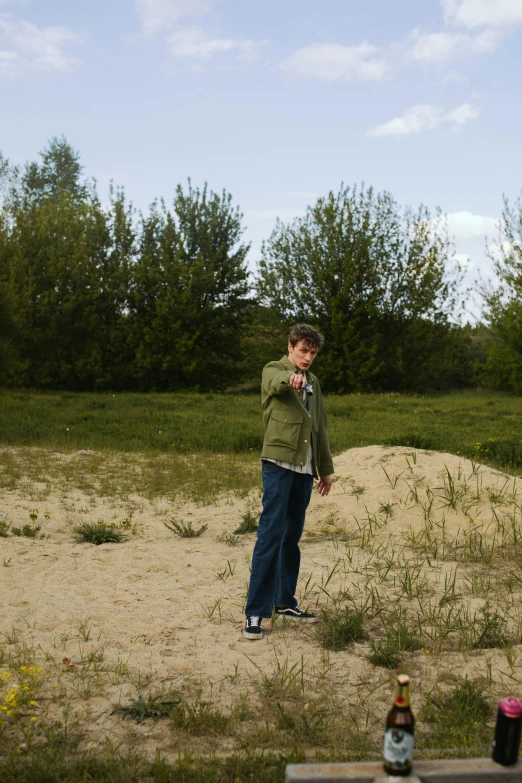 a man standing on top of a sandy field, an album cover, land art, tomboy, taken in the late 2010s, grassy, boyish