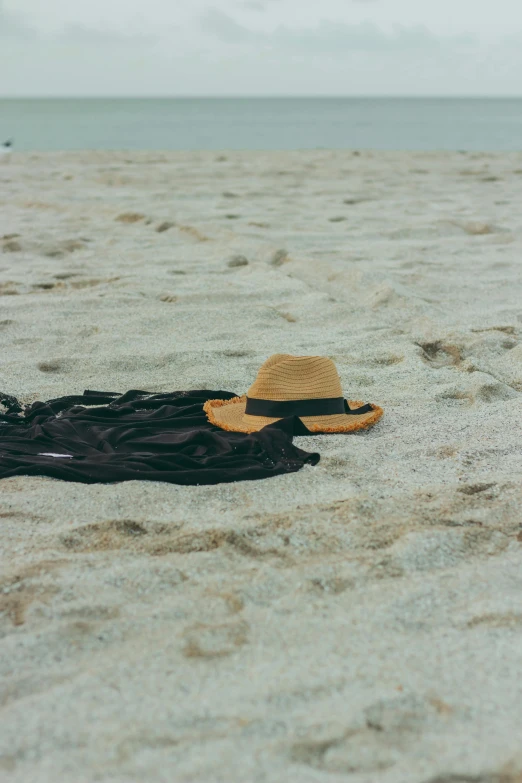 a hat sitting on top of a sandy beach, brown clothes, uncropped, ignant, floating robes