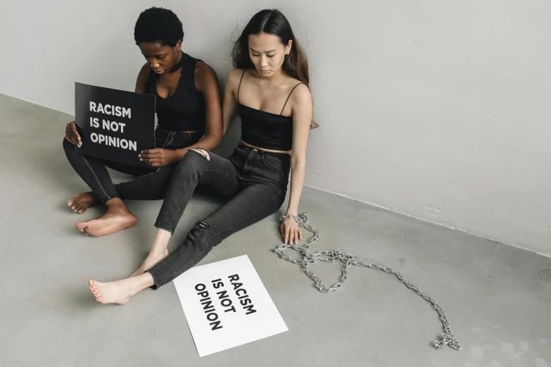 two women sitting on the floor holding a sign, inspired by Vanessa Beecroft, trending on unsplash, feminist art, neck chains, black teenage girl, ruan jia and brom, 15081959 21121991 01012000 4k