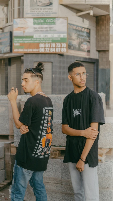 two men standing next to each other in front of a building, an album cover, unsplash contest winner, graffiti, wearing a black tshirt, mall goth, black teenage boy, profile pic