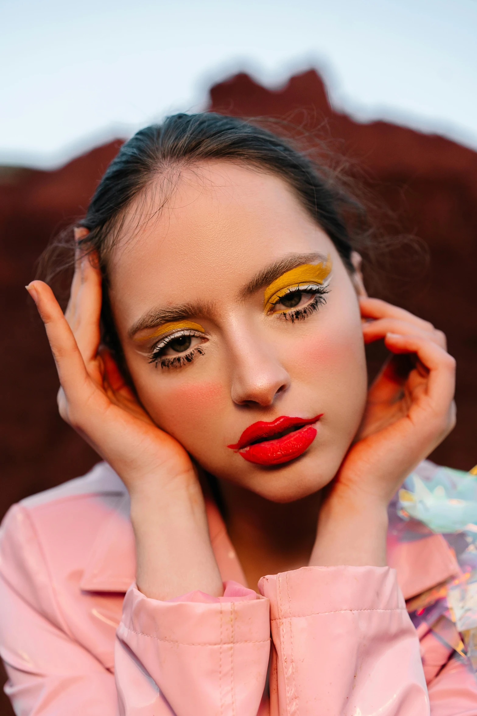 a woman is posing with her hands on her face, an album cover, by Julia Pishtar, trending on pexels, yellow makeup, coral lipstick, pastel', colorful with red hues