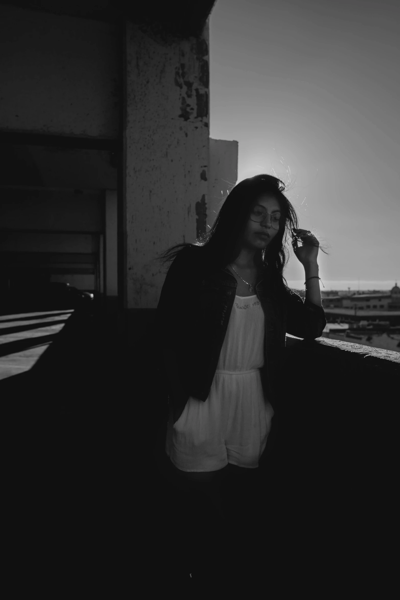 a woman standing on a balcony talking on a cell phone, a black and white photo, inspired by Elsa Bleda, unsplash, sun set, white on black, beautiful lonely girl, ruins