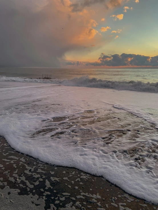 a large body of water sitting on top of a sandy beach, by Greg Rutkowski, storm in the evening, sea foam, during a sunset, profile image