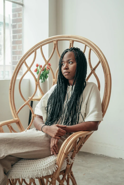 a woman sitting in a chair in front of a window, pexels contest winner, black arts movement, long flowing braided hair, gemma chen, nettie wakefield, sitting on an armchair