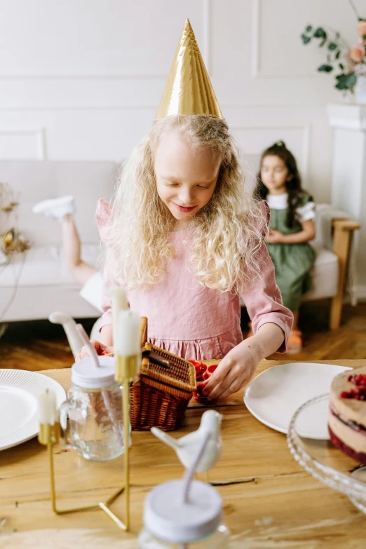 a little girl sitting at a table with a cake, pexels, happening, gold decorations, promo image, kids playing, girl standing