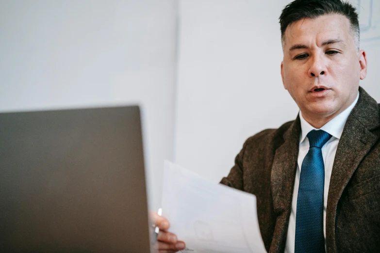 a man sitting in front of a laptop computer, pexels contest winner, lawyer clothing, holding a clipboard, man in his 40s, giving a speech