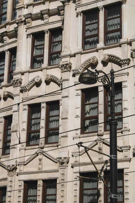 a street light sitting in front of a tall building, inspired by Mihály Munkácsy, trending on pexels, art nouveau, wires hanging across windows, exquisite marble details, elaborate hair, buenos aires