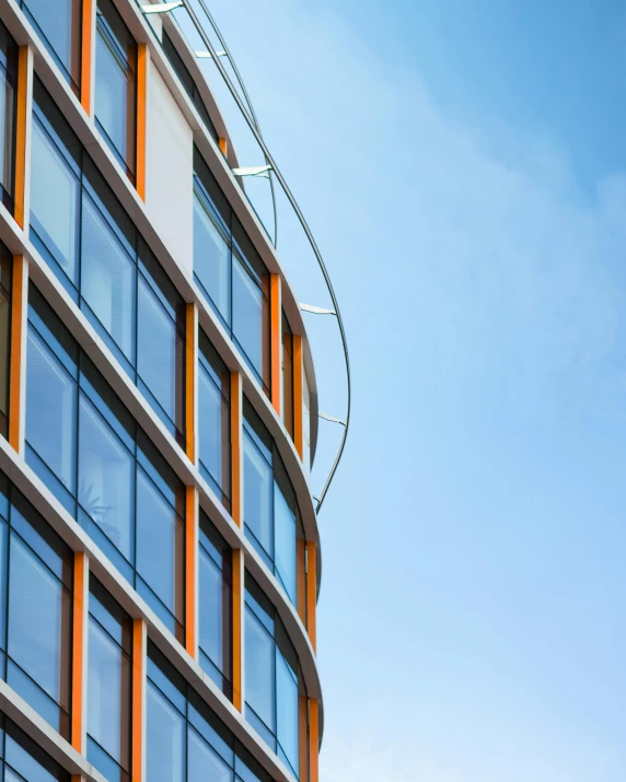 a clock on the side of a tall building, a screenshot, pexels contest winner, modernism, orange and blue, curved, wide windows, thumbnail