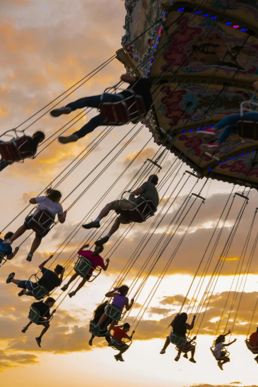 a group of people on a swing ride at sunset, flitting around in the sky, profile image, carousel, splash image