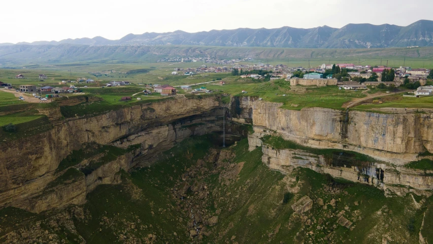 a group of people standing on top of a cliff, by Muggur, pexels contest winner, les nabis, located in hajibektash complex, deep sinkhole, view from the sky, citadel of erbil