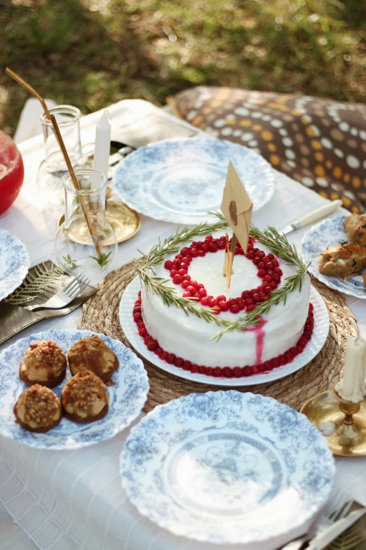 a table topped with plates of food and a cake, by Amalia Lindegren, maroon and blue accents, forest picnic, promo image, pomegranade