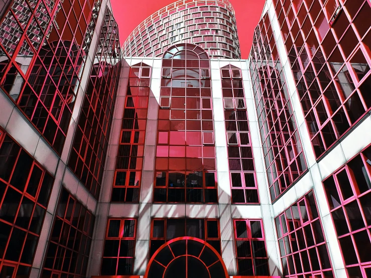 a very tall building with a red sky in the background, a photo, inspired by Ricardo Bofill, panfuturism, ((raytracing)), atrium, red grid, pink arches