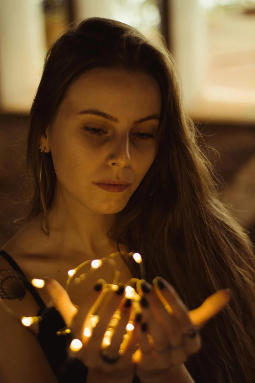 a woman holding a string of lights in her hands, pexels contest winner, light and space, pensive, 8k 50mm iso 10, sensual lighting, cinematic toplight