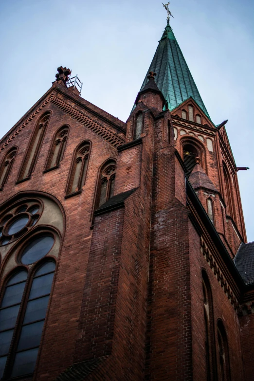 a tall red brick building with a green steeple, a photo, by Jan Tengnagel, unsplash, romanesque, marilyn church h, high-body detail, hannover, buttresses