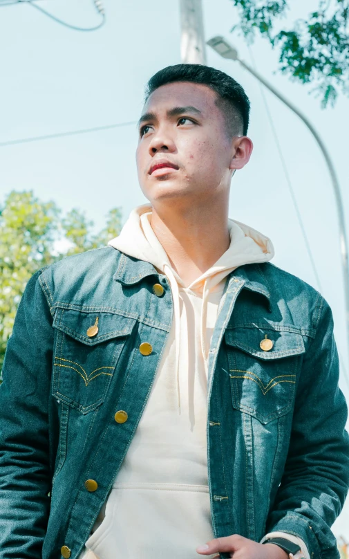 a man standing with his hands in his pockets, an album cover, inspired by Ryan Yee, pexels, realism, jean jacket, official screenshot, sunlight, medium head to shoulder shot