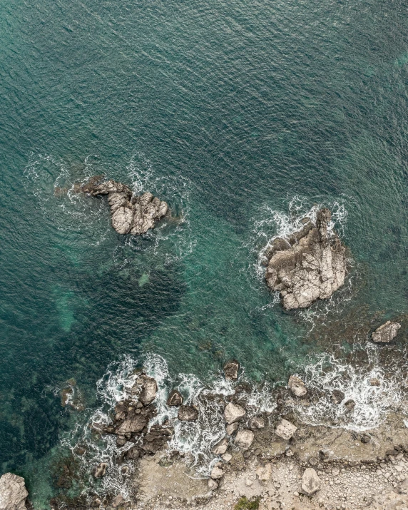 a large body of water next to a rocky shore, pexels contest winner, happening, top-down shot, ((rocks)), manly, high picture quality