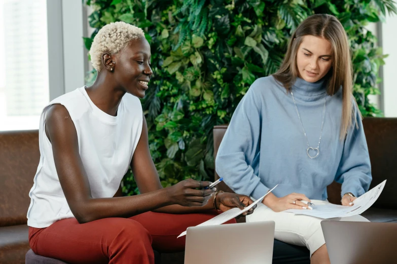 two women sitting on a couch with laptops, by Lee Loughridge, trending on pexels, hurufiyya, vibrant foliage, sitting on a mocha-colored table, sydney park, sitting in a waiting room