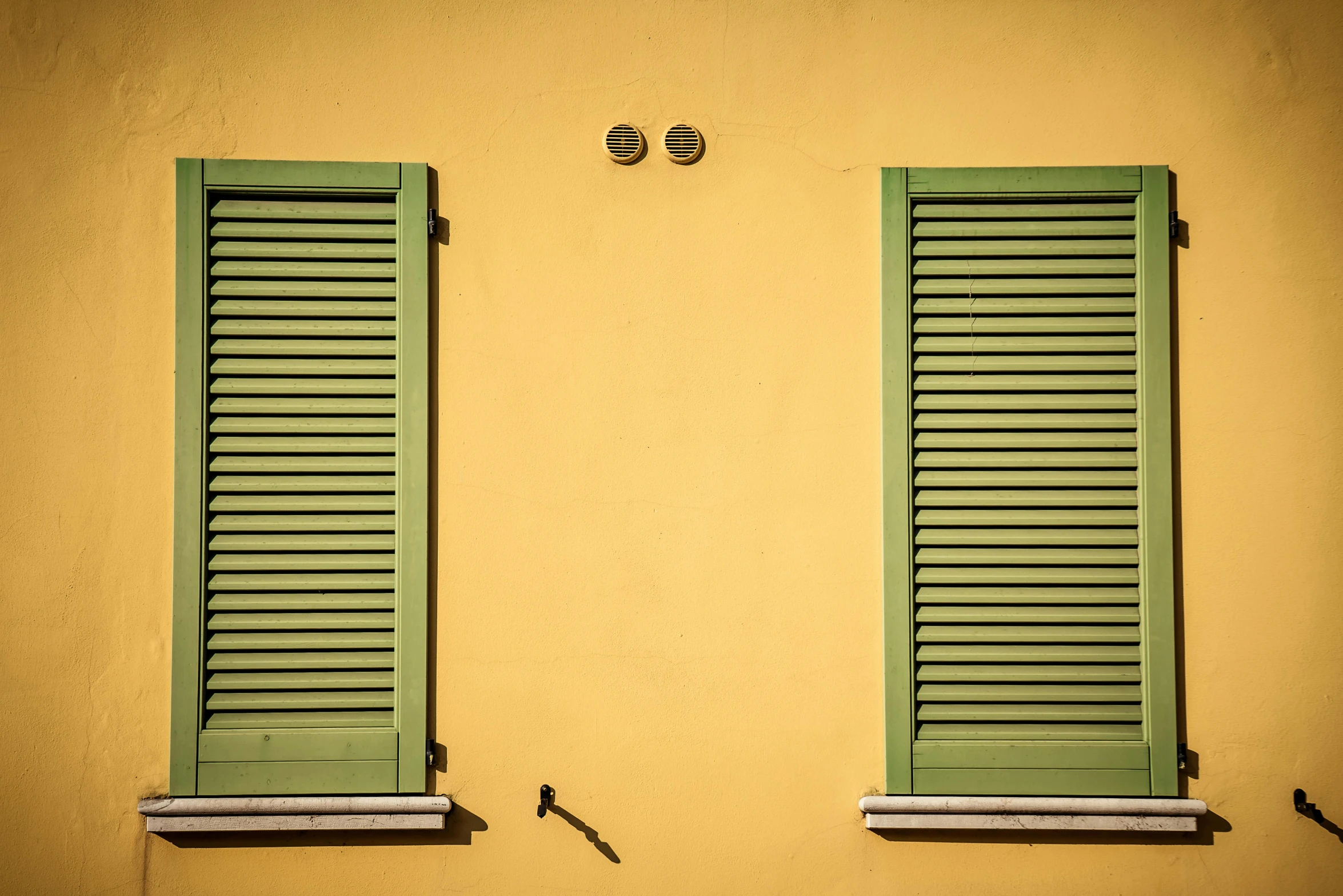 two green shutters on a yellow wall, a picture, pexels contest winner, light reflecting off windows, morandi color scheme, metal shutter, multicolored