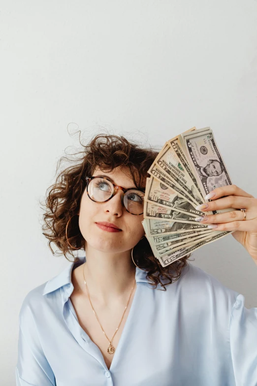 a woman holding a fan of money in front of her face, pexels contest winner, curly bangs, wearing square glasses, 🚀🌈🤩, tall thin