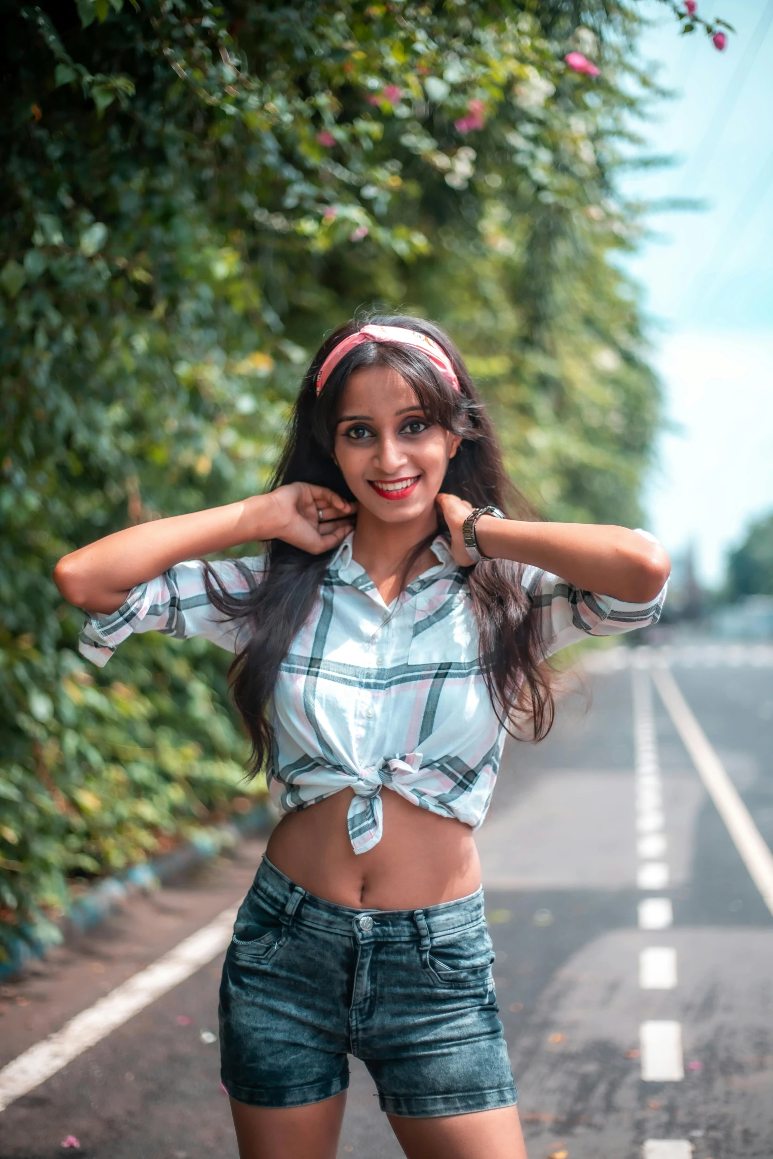 a woman standing on the side of a road, by Max Dauthendey, pexels contest winner, wearing a cropped tops, smiling at camera, flannel, avatar image