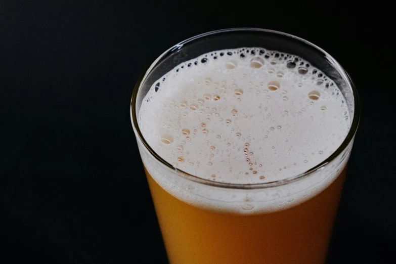 a glass of beer sitting on top of a table, with a black background, background image