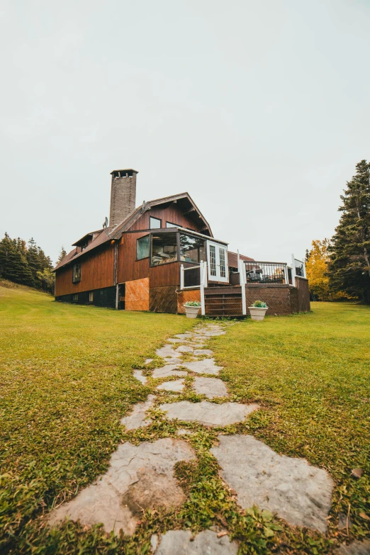 a house sitting on top of a lush green field, a colorized photo, unsplash, quebec, brown, wide angle full body, chalet