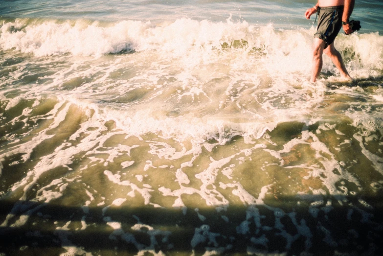 a man standing on top of a surfboard in the ocean, a picture, by Elsa Bleda, unsplash, greenish expired film, waves and splashes, teenage girl, scylla and charybdis