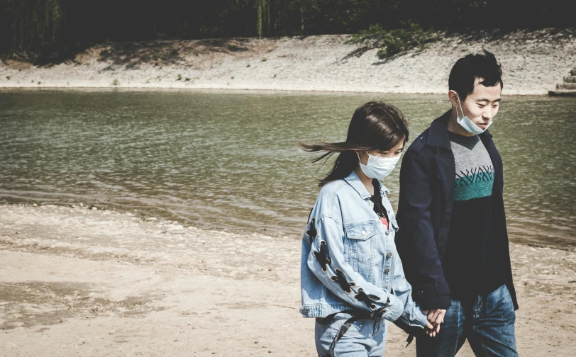a man and a woman walking next to a body of water, trending on pexels, surgical mask covering mouth, teenage girl, holding each other hands, gemma chen
