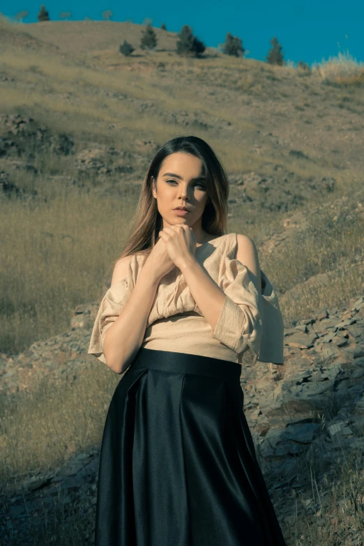 a woman standing on top of a grass covered hillside, an album cover, by irakli nadar, wearing elegant casual clothes, promotional image, leather clothing, in a valley