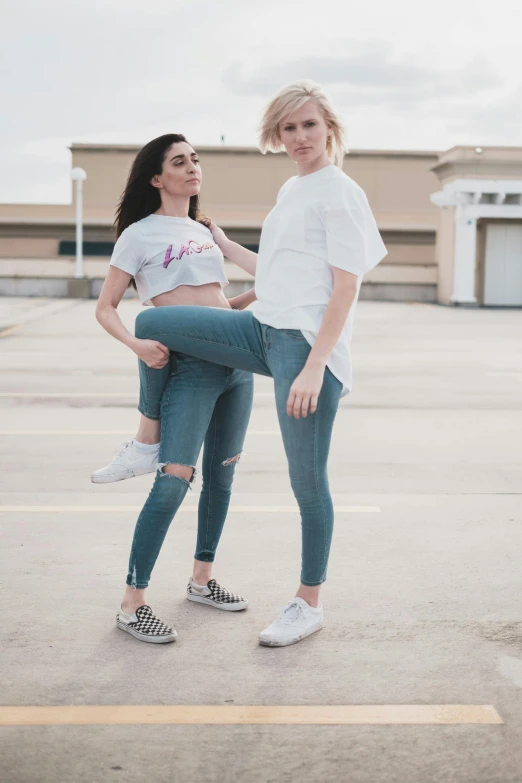 two women standing next to each other in a parking lot, by John Luke, trending on pexels, happening, jeans and t shirt, doing a majestic pose, bare leg, white background!!!!!!!!!!