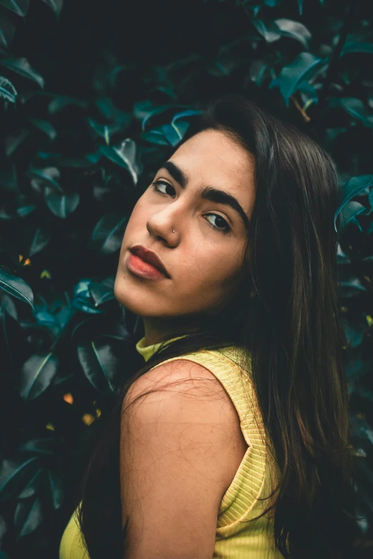 a beautiful young woman standing in front of a bush, inspired by Elsa Bleda, pexels contest winner, large eyebrows, alanis guillen, high angle closeup portrait, 5 0 0 px models