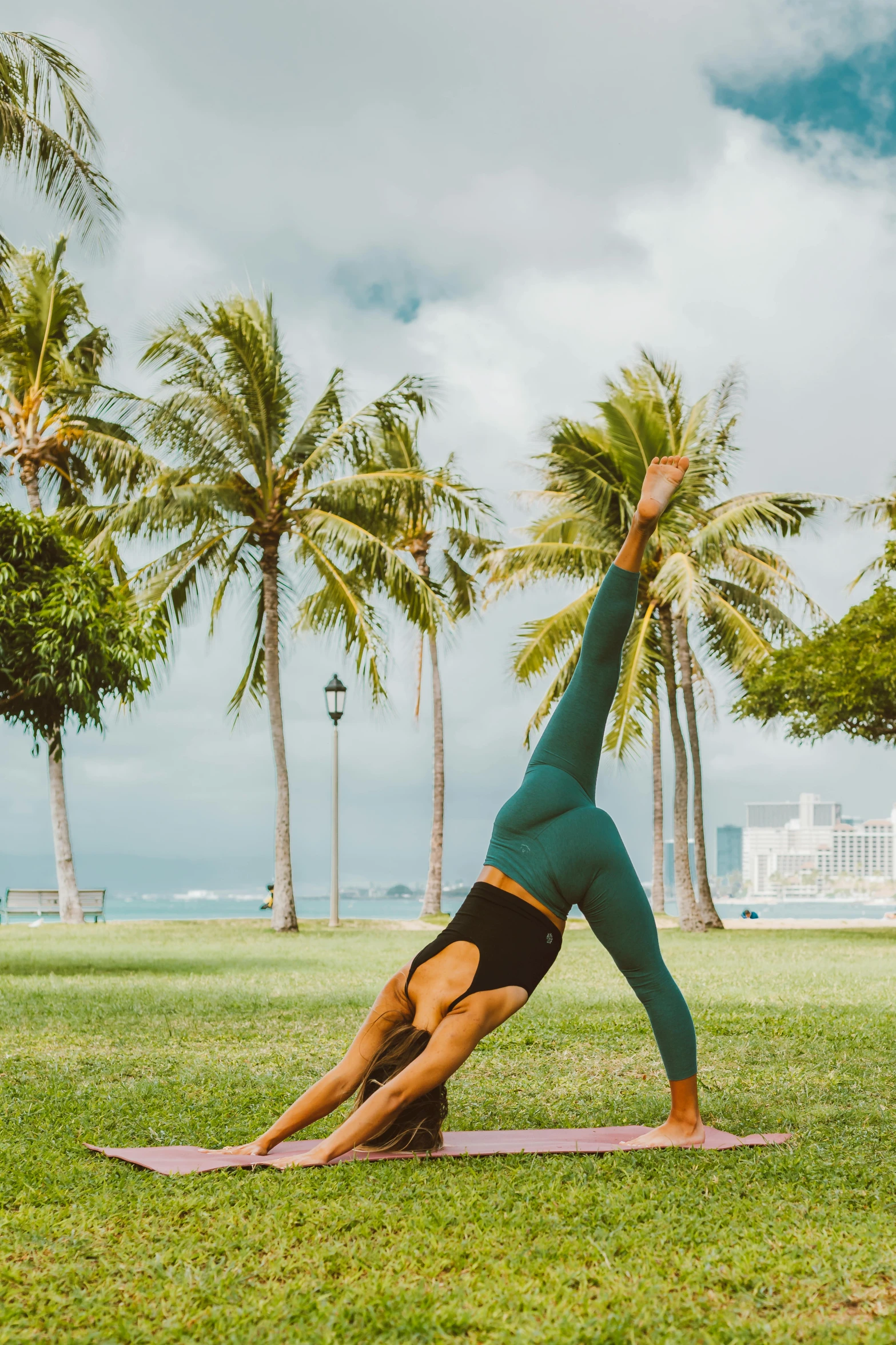 a woman doing a yoga pose in a park, by Jessie Algie, pexels contest winner, posing in waikiki, lawn, palm body, working out in the field