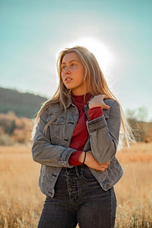 a woman standing in a field of tall grass, trending on pexels, wearing a jeans jackets, sydney sweeney, in a dusty red desert, wearing a turtleneck and jacket