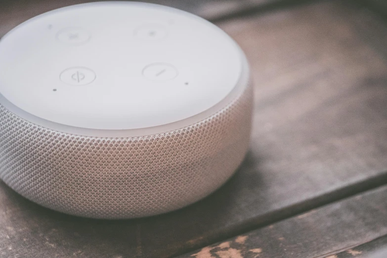 a smart speaker sitting on top of a wooden table, by Adam Marczyński, trending on pexels, graffiti, ivory, circular, polka dot, white plastic