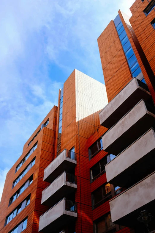 a couple of tall buildings sitting next to each other, a photo, inspired by Ricardo Bofill, unsplash, modernism, orange, bricks flying outwards, exterior view, square